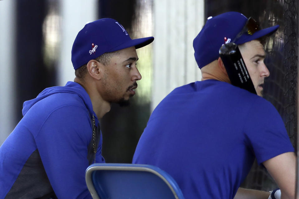 Los Angeles Dodgers outfielder Mookie Betts, left, waits with right fielder Joc Pederson, right, at the batting cages during spring baseball training Monday, Feb. 17, 2020, in Phoenix. (AP Photo/Gregory Bull)
