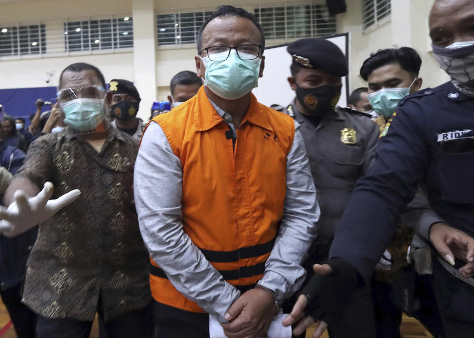 FILE - Indonesian Maritime Affairs and Fisheries Minister Edhy Prabowo, center, is escorted by security officers after a news conference at the Indonesian Corruption Eradication Commission (KPK) office in Jakarta, Indonesia, Nov. 26, 2020. Corruption is undermining the management of some of the world’s most threatened fishing grounds, according to a review of criminal case files and media reports by the AP. At least 45 government officials have been accused of graft or extortion in the past two decades. (AP Photo/File)