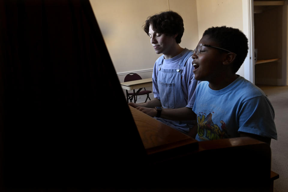 Grayson Hart and cast member Evan Roberts, 11, rehearse a song at the Ned R. McWherter West Tennessee Cultural Arts Center in Jackson, Tenn., on Saturday, March 4, 2023. Hart, who directs a youth theater program, was accepted into every college he applied to, but turned them down. He is one of thousands of young adults who graduated high school during the pandemic and are taking career routes other than college. (AP Photo/Mark Zaleski)