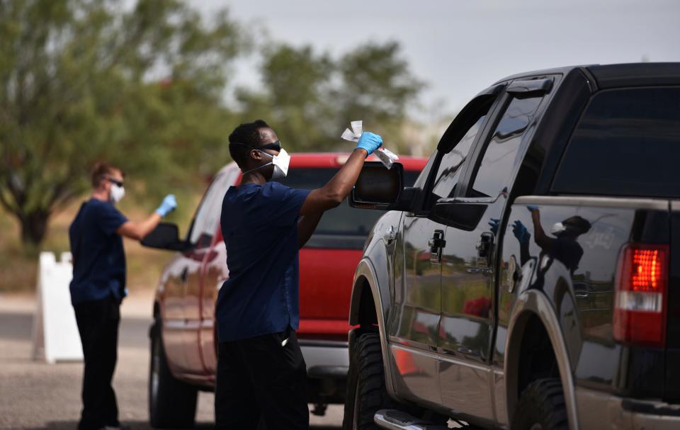 National Guard Specialist Shumirai Tsikada, right, passes a coronavirus testing kit through the window of truck at the West Side Senior Activity Center in Odessa, Texas on Wednesday, July 1, 2020.