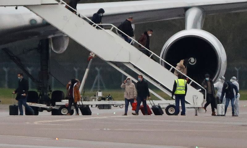 Passengers from China disembark from a plane at RAF Brize Norton near Oxford