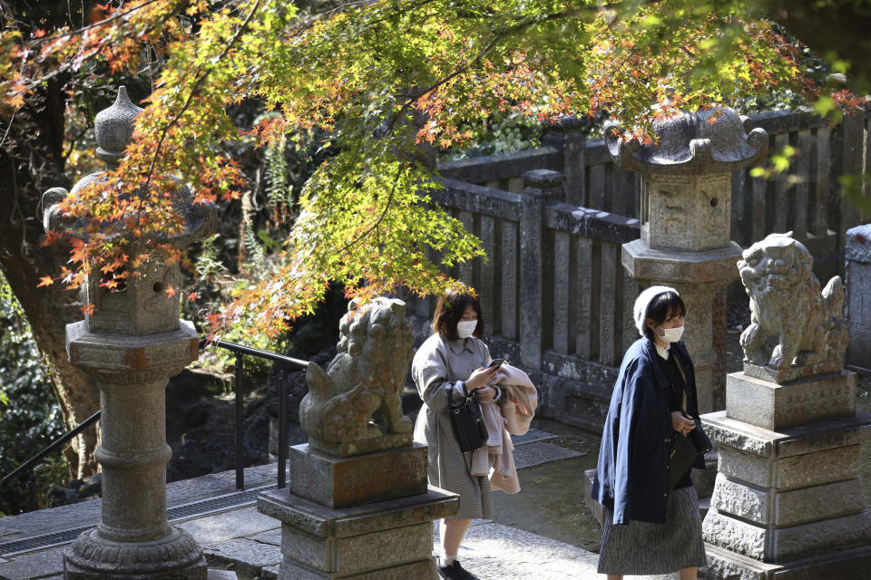 Visitors wearing face masks to protect against the spread of the coronavirus walk through the colorful autumn leaves at the Kenchoji temple in Kamakura, Monday, Nov. 30, 2020. (AP Photo/Koji Sasahara)