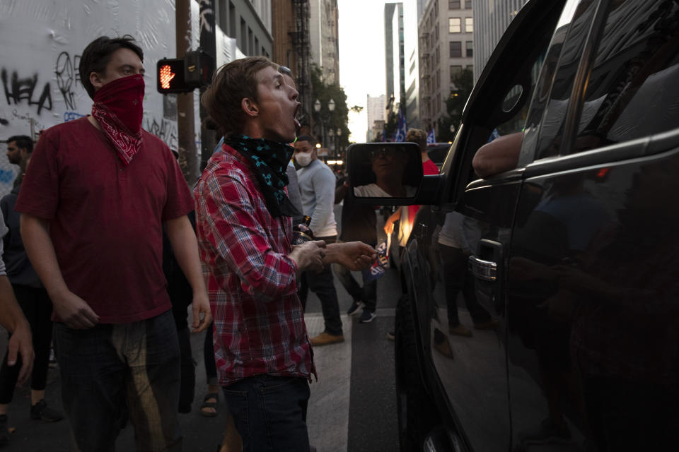 A Black Lives Matter protester yells at a supporter of President Donald Trump during a rally and car parade Saturday, Aug. 29, 2020, in Portland, Ore. One person was shot and killed late Saturday in Portland as a large caravan of President Donald Trump supporters and Black Lives Matter protesters clashed in the streets, police said. It wasn’t clear if the shooting was linked to fights that broke out as a caravan of about 600 vehicles was confronted by protesters in the city’s downtown. (AP Photo/Paula Bronstein)