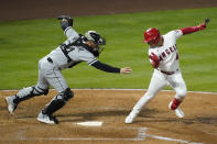 Los Angeles Angels shortstop Jose Iglesias (4) avoids a tag attempt by Chicago White Sox catcher Yasmani Grandal (24) during the fourth inning of an MLB baseball game Friday, April 2, 2021, in Anaheim, Calif. Iglesias was out at first. (AP Photo/Ashley Landis)