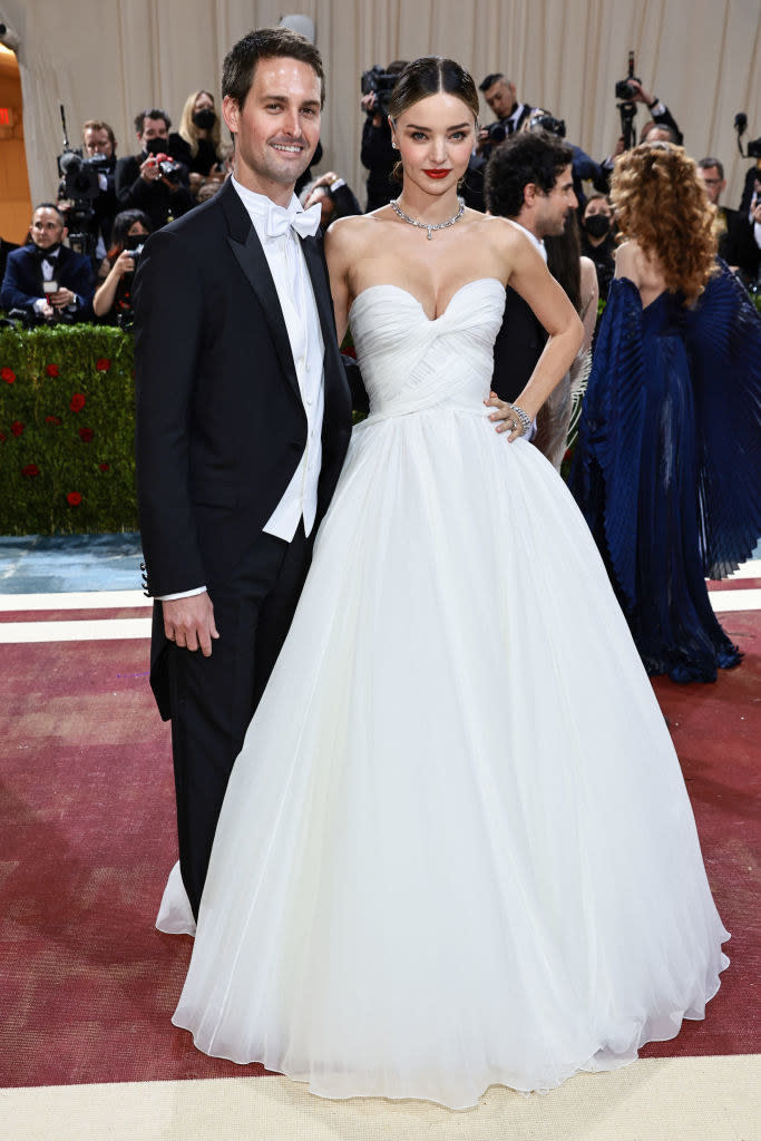 Evan Spiegel and Miranda Kerr stand together and smile on the red carpet