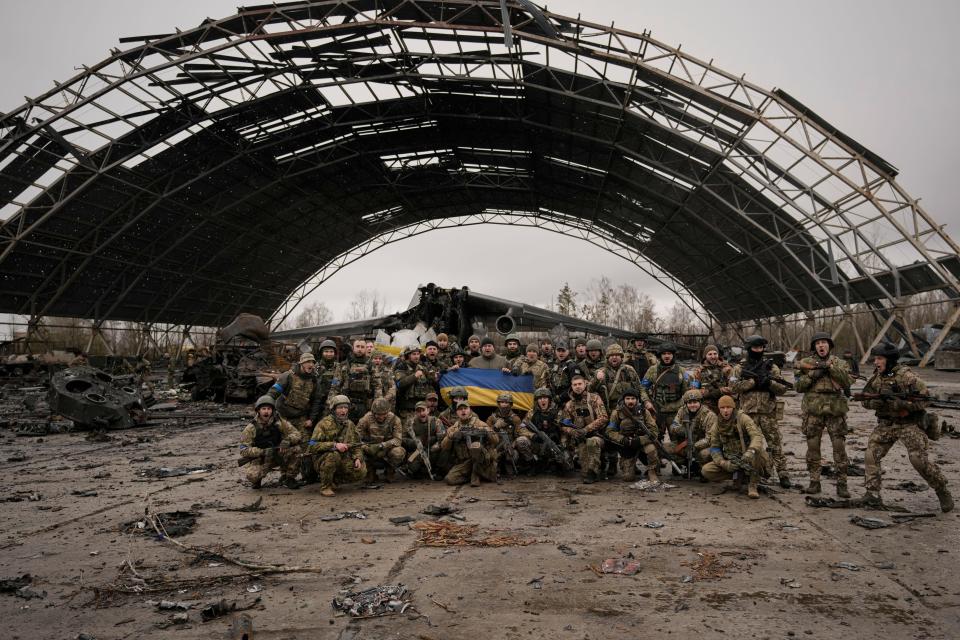 Ukrainian servicemen shout patriotic slogans backdropped by the destroyed Antonov An-225 Mriya aircraft.