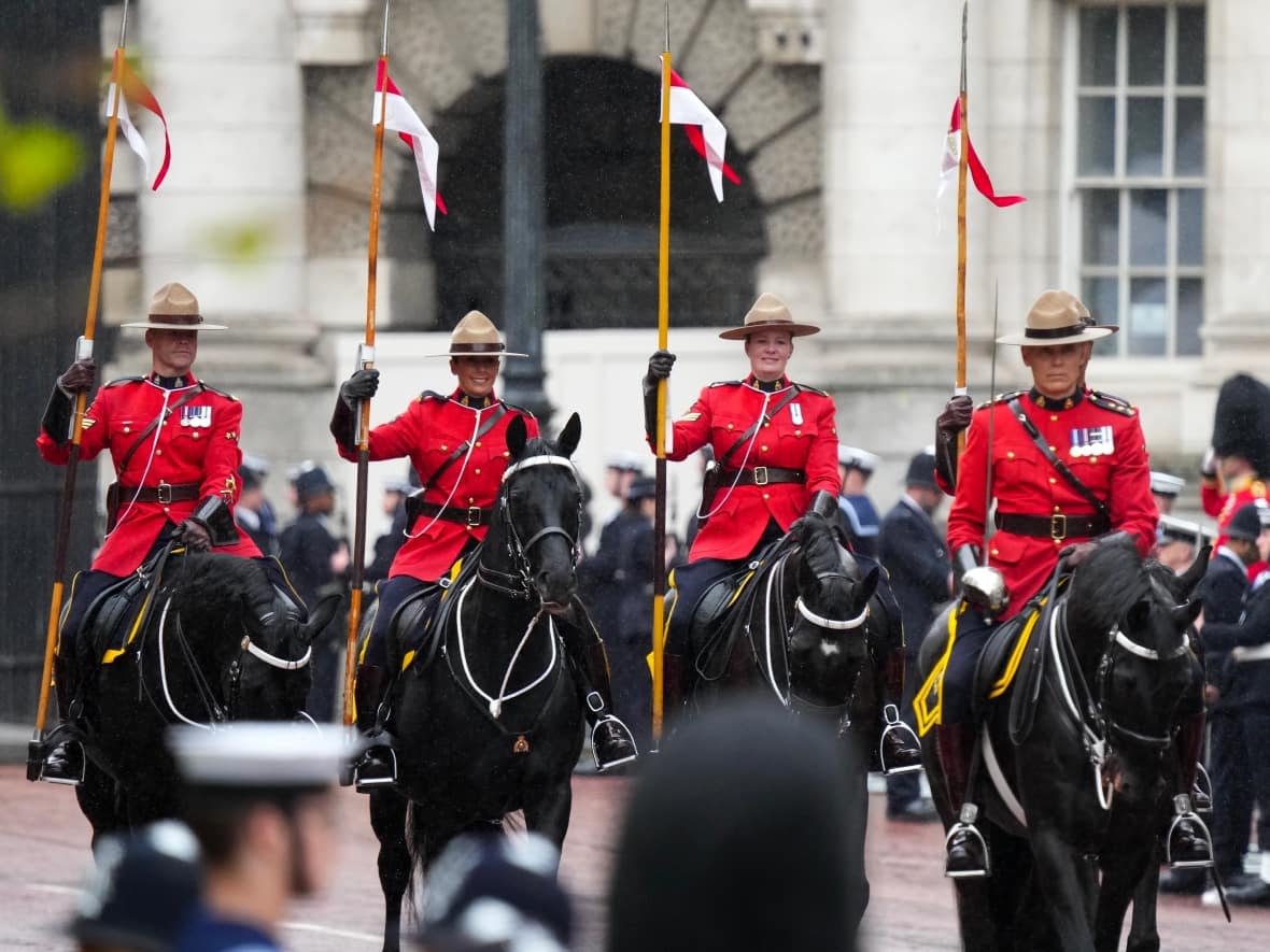 RCMP officers ride in front of King Charles and Queen Camilla’s carriage during the royal procession following the coronation ceremony in London on Saturday. (Nathan Denette/The Canadian Press - image credit)