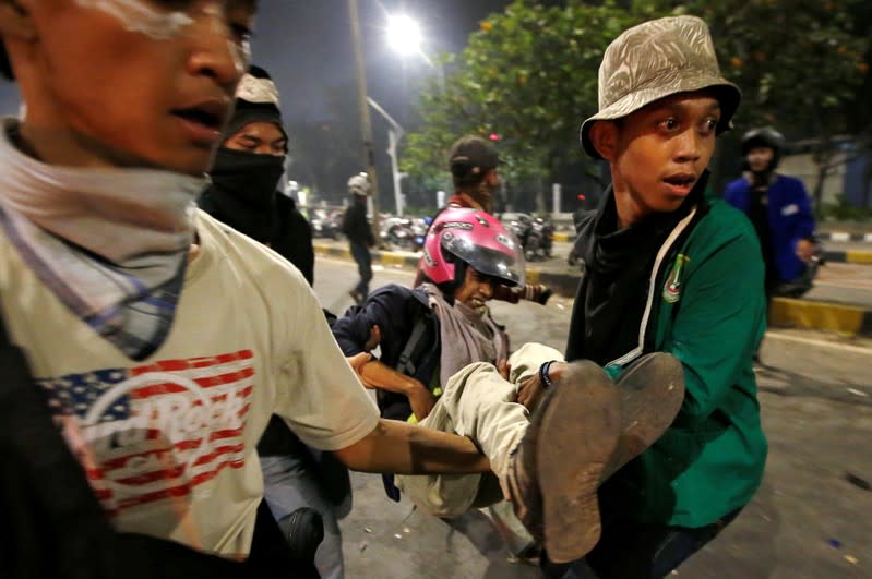 FILE PHOTO: A demonstrator is carried during a protest by university students outside the Indonesian parliament in Jakarta, Indonesia