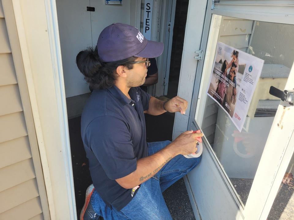 Oscar Lopez, who is part of a canvassing team working with the Massachusetts Health Connector, places a sign inside the door of Framingham Baking Company at 840 Waverly St. in Framingham. Lopez and his team were spreading the word about health insurance options for residents who live in underinsured neighborhoods.