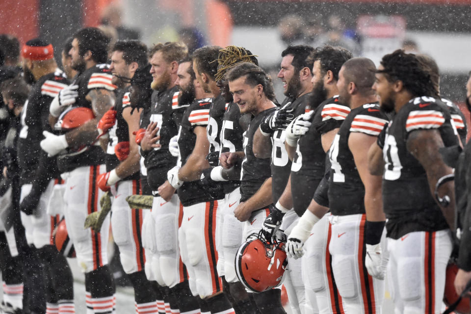 Members of the Cleveland Browns stand for the national anthem as it rains and hails before an NFL football game against the Houston Texans, Sunday, Nov. 15, 2020, in Cleveland. The game was delayed due to lightning. (AP Photo/David Richard)