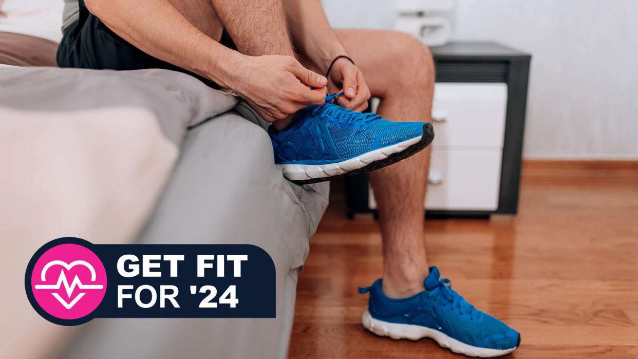  Man laces up trainers while sitting on the edge of the bed. 