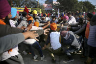 Protesting farmers remove a concrete barricade set up by policemen, as they attempt to move towards Delhi, at the border between Delhi and Haryana state, Friday, Nov. 27, 2020. Thousands of agitating farmers in India faced tear gas and baton charge from police on Friday after they resumed their march to the capital against new farming laws that they fear will give more power to corporations and reduce their earnings. While trying to march towards New Delhi, the farmers, using their tractors, cleared concrete blockades, walls of shipping containers and horizontally parked trucks after police had set them up as barricades and dug trenches on highways to block roads leading to the capital. (AP Photo/Altaf Qadri)