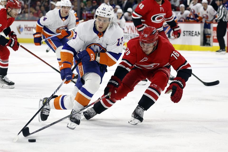 New York Islanders' Mathew Barzal (13) tries to control the puck as he battles Carolina Hurricanes' Brady Skjei (76) during the first period of an NHL hockey game in Raleigh, N.C., Saturday, Dec. 23, 2023. (AP Photo/Karl B DeBlaker)