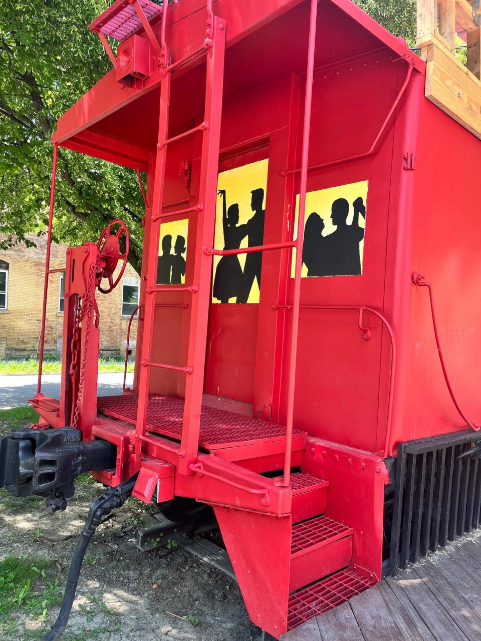 The now-permanently sealed windows on the Downtown Alliance Caboose have been decorated with images that depict couples dancing. The caboose these days is used as a stage for free outdoor concerts.