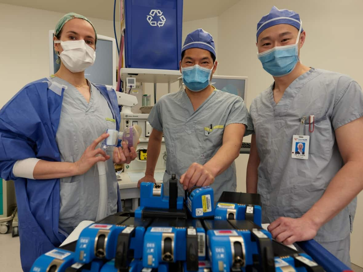 Anesthesiologists Drs. Paula Meyler, Cedric Ho, and Alex Suen display a number of desflurane vaporizers shortly before the devices were removed from Royal Columbian Hospital. (Royal Columbian Hospital - image credit)