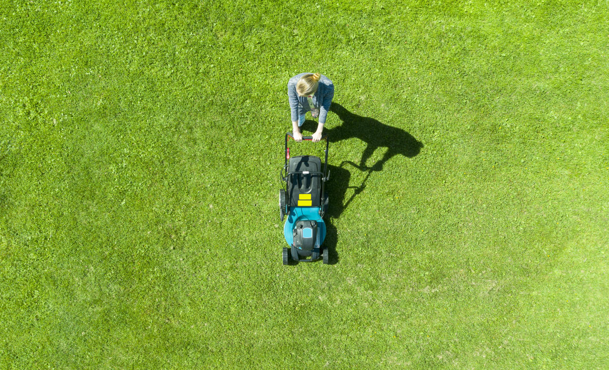 Greenworks 14-Inch 9 Amp Corded Lawn Mower MO09B01, Beautiful girl cuts the lawn. Mowing lawns. Aerial view beautiful woman lawn mower on green grass. Mower grass equipment. Mowing gardener care work tool. Close up view. Aerial lawn mowing