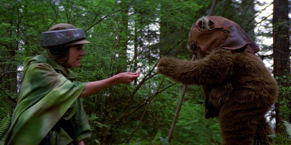 Princess Leia (Carrie Fisher) giving Wicket (Warwick Davis) some food.