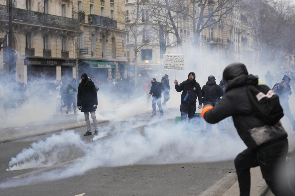 Protesters stand amid tear gas during an incident aspart of a demonstration against plans to push back France's retirement age, Tuesday, Jan. 31, 2023 in Paris. Labor unions aimed to mobilize more than 1 million demonstrators in what one veteran left-wing leader described as a "citizens' insurrection." The nationwide strikes and protests were a crucial test both for President Emmanuel Macron's government and its opponents. (AP Photo/Thibault Camus)