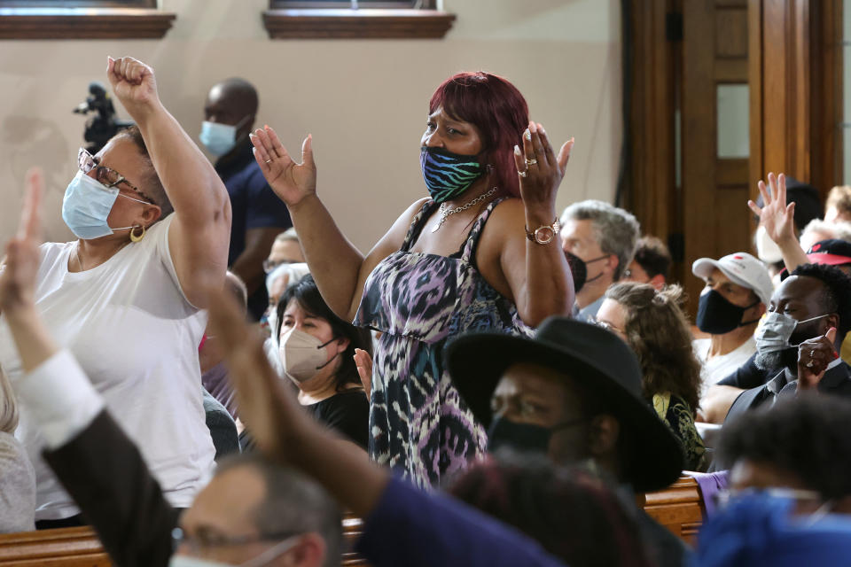 Participants stand and raise their hands skyward at an interfaith service.