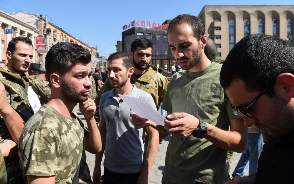 People attend a meeting to recruit military volunteers after Armenian authorities declared martial law and mobilised its male population following clashes with Azerbaijan - MELIK BAGHDASARYAN /REUTERS