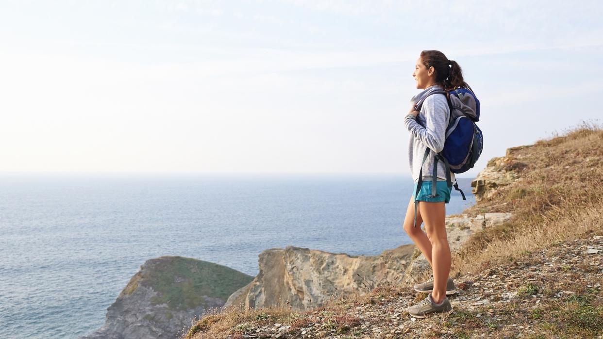  Hiker standing on cliff overlooking sea 