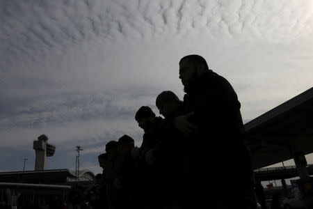 Men stand in silhouette during the Jummah prayer of an interfaith event outside Terminal 4 at John F. Kennedy Airport in New York, U.S., February 3, 2017. REUTERS/Shannon Stapleton