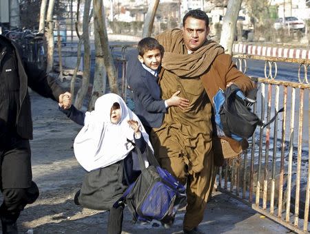 A man carries his son as they run after a blast near the Pakistani consulate in Jalalabad, Afghanistan January 13, 2016. REUTERS/Parwiz
