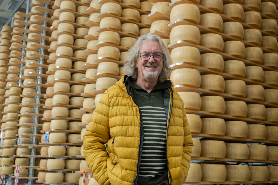 James May standing in front of piles of cheese rounds in Italy