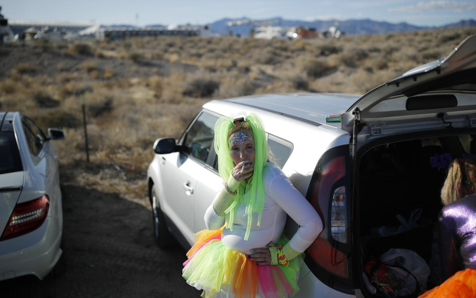 Alex Clark smokes a cigarette outside of the Storm Area 51 Basecamp event Friday, Sept. 20, 2019, in Hiko, Nev. The event was inspired by the "Storm Area 51" internet hoax. Thousands of curious Earthlings from around the globe traveled to festivals, and several hundred made forays toward the secret Area 51 military base in the Nevada desert on Friday, drawn by an internet buzz and a social media craze sparked by a summertime Facebook post inviting people to “Storm Area 51.” (AP Photo/John Locher)