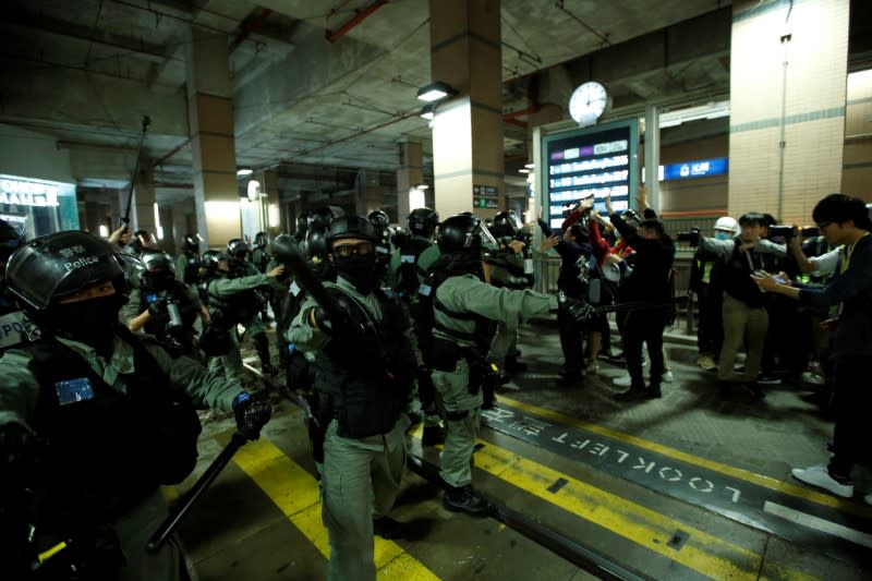 Police officers brandish pepper spray to disperse protesters who gathered at the site of an attack six months ago by an armed mob on anti-government demonstrators at the district of Yuen Long in Hong Kong