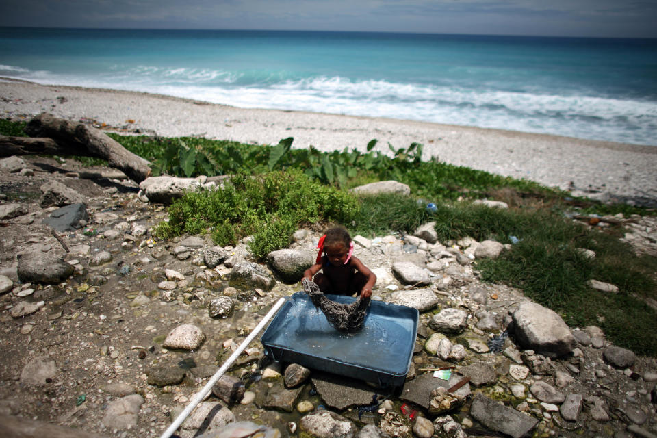 A girl rinses out a mop head along the shore in Barahona, Dominican Republic, Thursday, Aug. 23, 2012. Puerto Rico and the U.S. Virgin Islands braced for torrential rains on Thursday as Tropical Storm Isaac whipped up waves as high as 10 feet (3 meters) in the Caribbean and threatened to become a hurricane that could take a shot at Florida just as Republicans gather for their national convention. (AP Photo/Ricardo Arduengo)