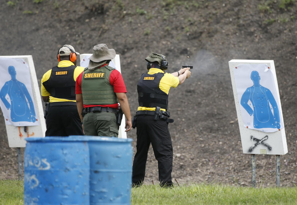 In this Monday, July 30, 2018 photo, a Broward Sheriff's Office (BSO) trainer, center, watches two Broward County Public Schools newly-hired armed guardians during firearms training at BSO's gun range at Markham Park in Sunrise, Fla. Twenty-two of the Florida school districts are supplementing officers with "guardians" - armed civilians or staff. They are vetted, receive 132 hours of training and must attain a higher score on the state firearms test than rookie police officers. (AP Photo/Wilfredo Lee)