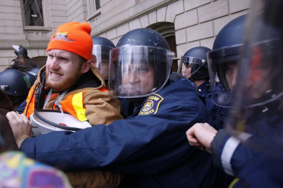 Dan Fingas, 30, of Ann Arbor, a union representative with the Michigan Laborers Union struggles with the Michigan State Police during a protest against right-to-work legislation outside the Capitol in Lansing, Mich.,  Tuesday, Dec. 11, 2012.