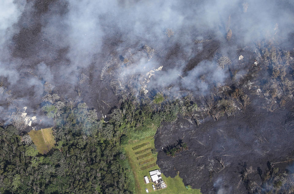 Lava from volcanic fissures slowly flows and overtakes structures and trees in Leilani Estates&nbsp;on Sunday.