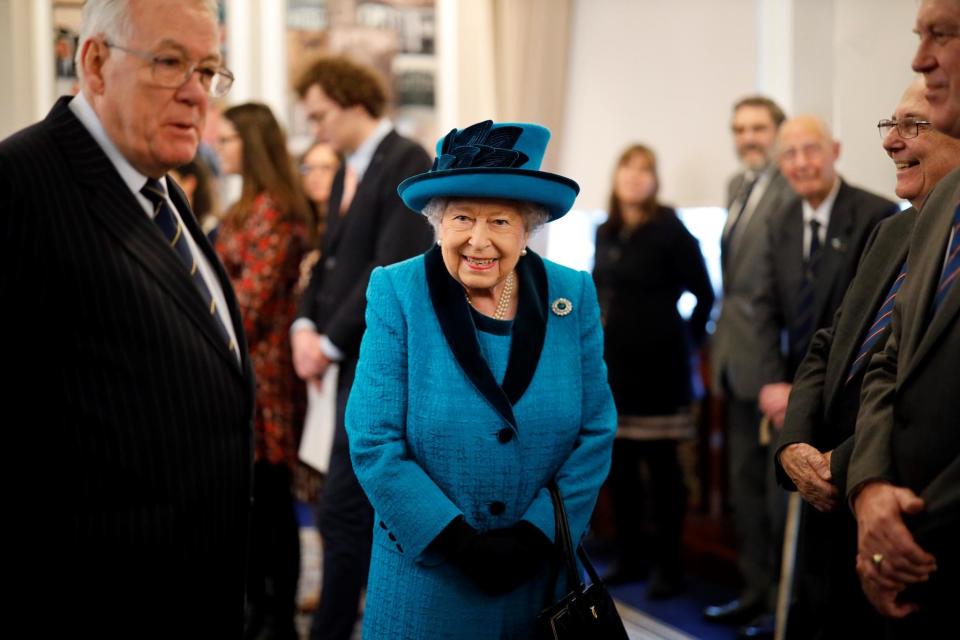 Queen Elizabeth II accompanied by Richard Stock, president of the Royal Philatelic Society, speaks with members as she visits the society's new headquarters on 26 November: Getty