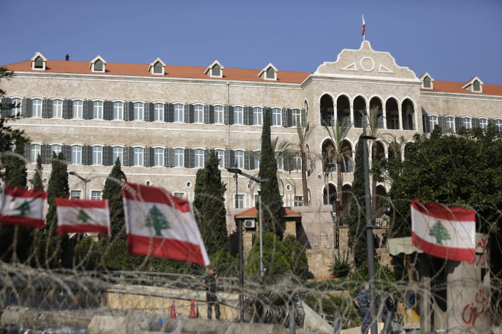 Policemen stand behind barricades that were installed as extra security measures around the Lebanese government building, background, Beirut, Lebanon, Saturday, Oct. 19, 2019. The blaze of protests was unleashed a day earlier when the government announced a slate of new proposed taxes, including a $6 monthly fee for using Whatsapp voice calls. The measures set a spark to long-smoldering anger against top leaders from the president and prime minister to the numerous factional figures many blame for decades of corruption and mismanagement. (AP Photo/Hassan Ammar)