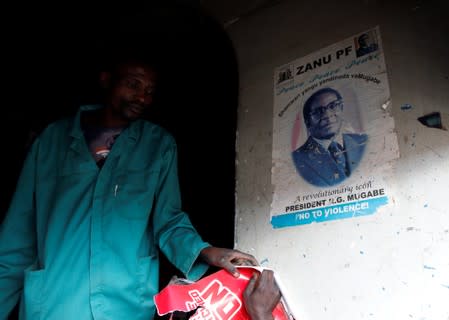 A man walks past a portrait of late former Zimbabwe's President Robert Mugabe, at a groceries store in Mbare township, Harare