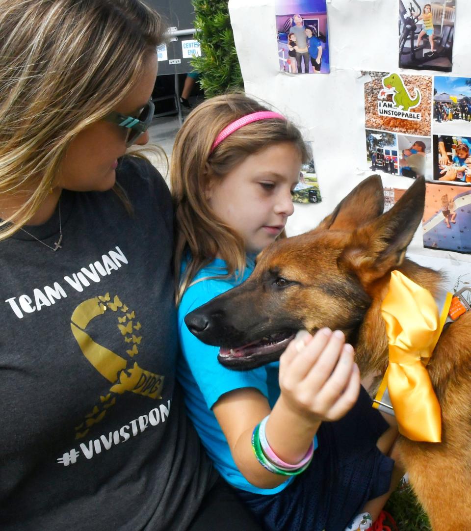 Viv Sleeth, who suffers from a rare form of pediatric brain-stem cancer, pets the Titusville Police Department's new K9 puppy during Sunday's head-shaving event in Rockledge.