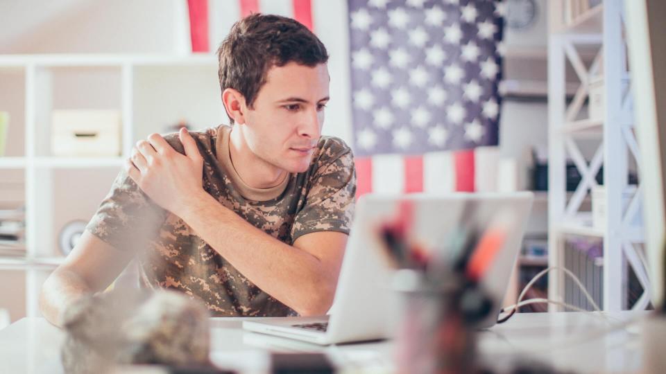 Young soldier man using a computer into his office.