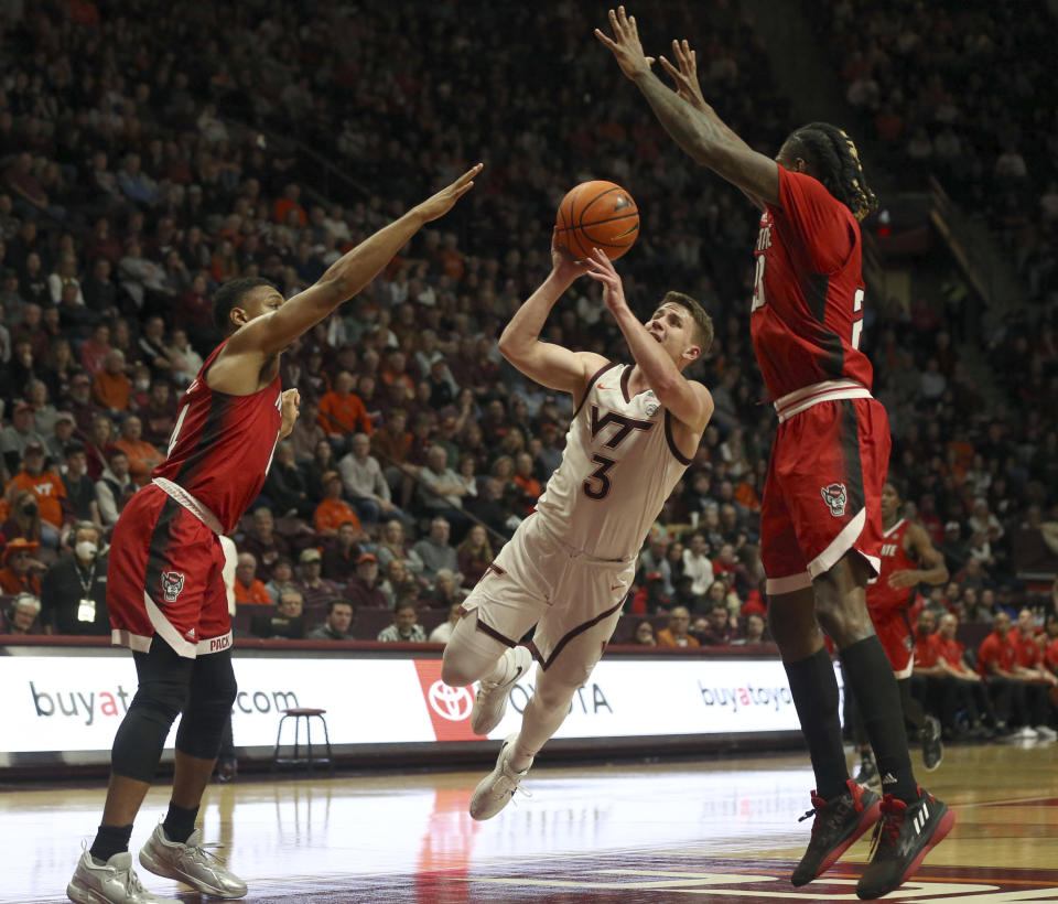 Virginia Tech's Sean Pedulla (3) center, attempts a shot while defended by North Carolina State's Casey Morsell, left, and Greg Gantt during the second half of an NCAA college basketball game Saturday, Jan. 7, 2023, in Blacksburg, Va. (Matt Gentry/The Roanoke Times via AP)