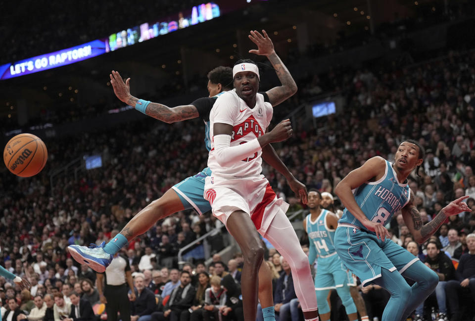 Toronto Raptors forward Chris Boucher, front left, watches as the ball from Charlotte Hornets forward P.J. Washington, back left, flies off while Hornets guard Nick Smith Jr. (8) looks on during second-half NBA basketball game action in Toronto, Monday, Dec. 18, 2023. (Nathan Denette/The Canadian Press via AP)