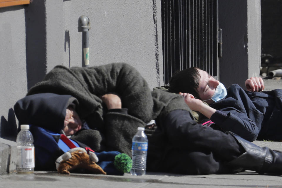 A man wearing a mask sleeps near another person on a sidewalk near the Union Gospel Mission on Friday. (Photo: Ted S. Warren/ASSOCIATED PRESS)