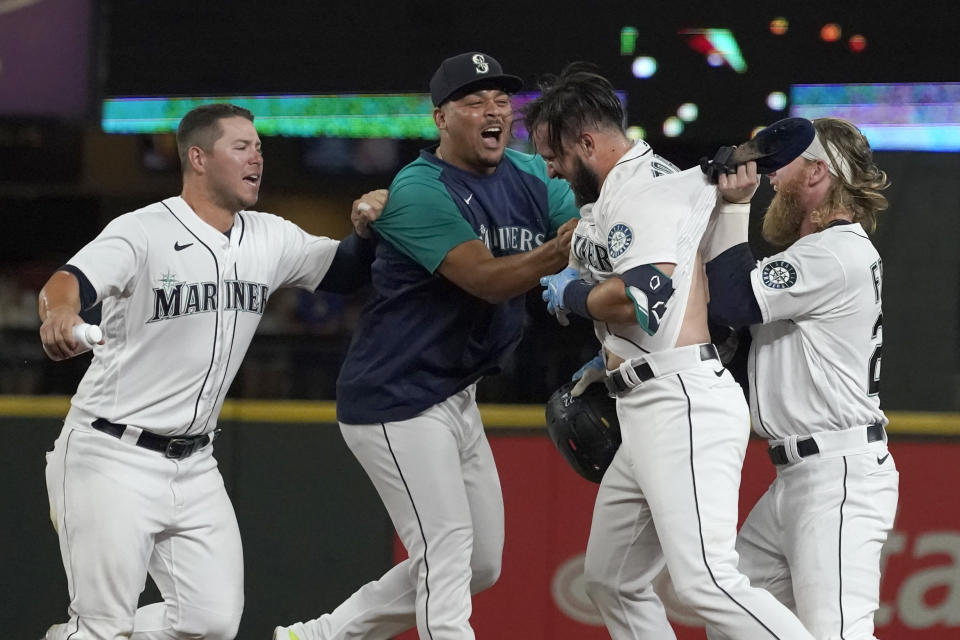 Seattle Mariners' Luis Torrens, second from right, is congratulated by teammates after his single scored Jarred Kelenic with the winning run during the ninth inning of the team's baseball game against the Texas Rangers, Wednesday, Aug. 11, 2021, in Seattle. The Mariners won 2-1. (AP Photo/Ted S. Warren)