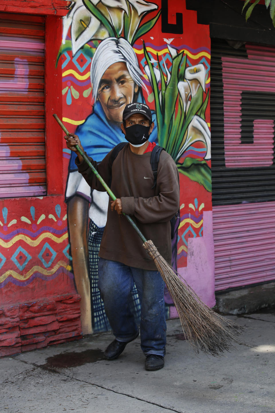 Wearing a mask to curb the spread of the new coronavirus, a street sweeper works in the Iztapalapa Borough of Mexico City, Monday, Aug. 9, 2021. Mexico will ask the United States to send at least 3.5 million more doses of COVID-19 vaccine as the country faces a third wave of infections, President Andres Manuel Lopez Obrador said Monday. (AP Photo/Marco Ugarte)