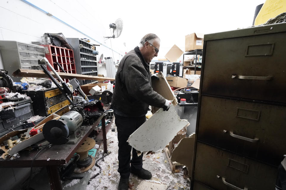 David Hurdt clears debris in his workshop Sunday, Dec. 10, 2023 in Hendersonville, Tenn. Central Tennessee residents and emergency workers are continuing the cleanup from severe storms and tornadoes that hit the area. (AP Photo/George Walker IV)