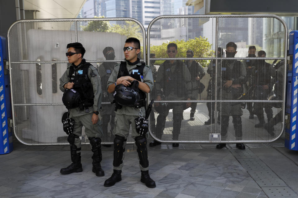 Policemen watch the Legislative Council building as people take part in a "No Tear Gas" rally march in Hong Kong, Sunday, Dec. 1, 2019. About 200 people are marching against police use of tear gas as Hong Kong readies for a day of protests. The group carried yellow balloons as they headed Sunday morning from Edinburgh Square to the nearby government headquarters. (AP Photo/Vincent Thian)