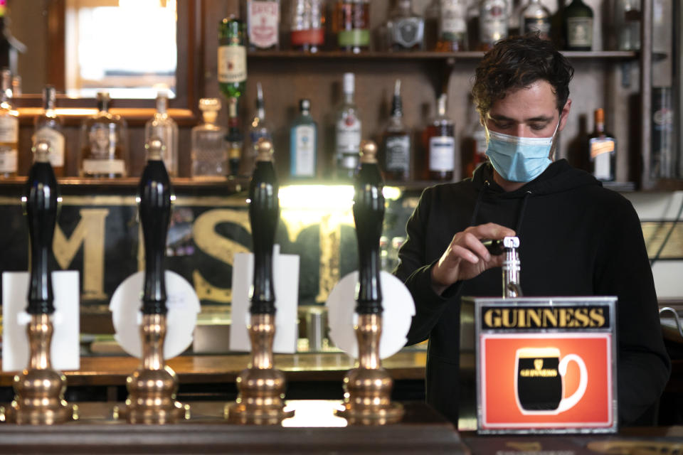 A member of staff pours a drink, at the Dispensary pub in Liverpool, England, Monday Oct 12, 2020. The British government has carved England into three tiers of risk in a bid to slow the spread of a resurgent coronavirus. The northern city of Liverpool is in the highest category and will close pubs, gyms and betting shops. (AP Photo/Jon Super)