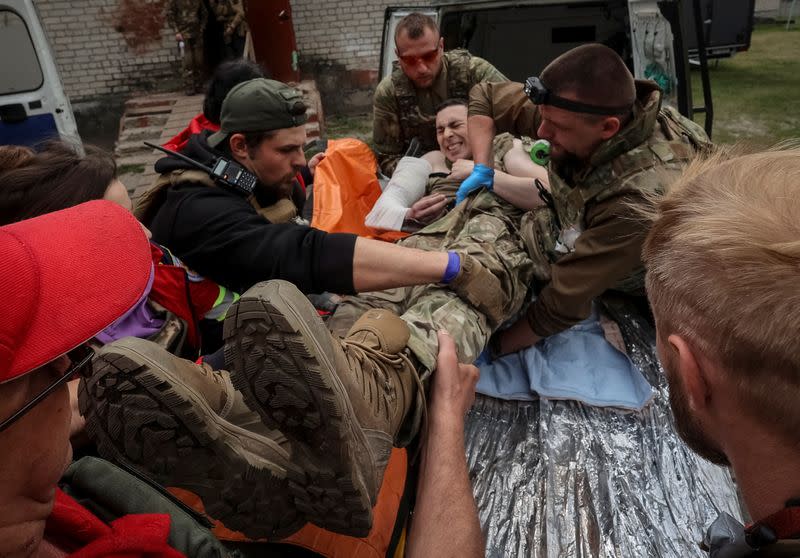 Medical workers and servicemen treat a wounded Ukrainian service member near the town of Vovchansk