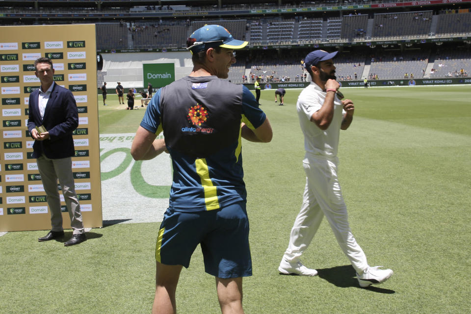 Australian captain Tim Paine, center, and his India counterpart Virat Kohli walk past each other without acknowledgement during the post match interviews following the second cricket test between Australia and India in Perth, Australia, Tuesday, Dec. 18, 2018. (AP Photo/Trevor Collens)