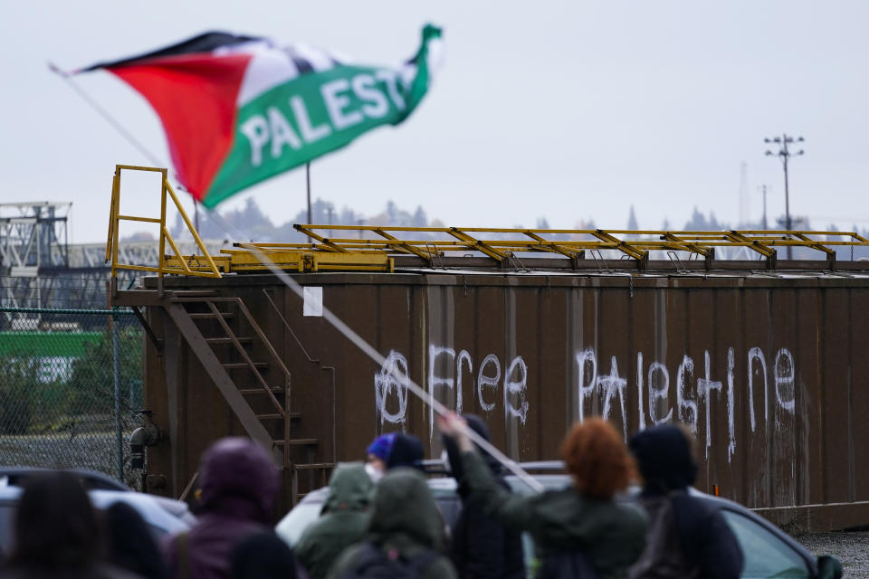 A protester waves a Palestinian flag as people block the Port of Tacoma entrances as they attempt to delay the loading of the MV Cape Orlando Monday, Nov. 6, 2023, in Tacoma, Wash. Hundreds of protesters calling for a cease-fire in Gaza are blocking traffic at the Port of Tacoma, where a military supply ship had recently arrived. (AP Photo/Lindsey Wasson)